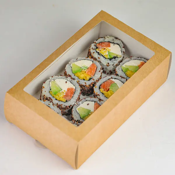 A box filled with sushi is placed on top of a clean white table, ready to be enjoyed.