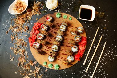 Bir tabak dolusu suşi ve ahşap bir masaya yerleştirilmiş yemek çubukları..