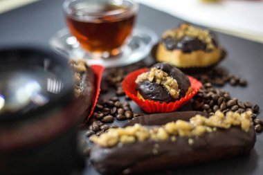 Lezzetli çikolata kaplı çörekler sergilenen bir masa, ferahlatıcı bir fincan çayın yanında..