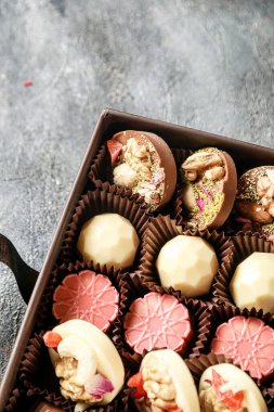 Masada çeşitli çikolatalarla dolu bir kutu duruyor..