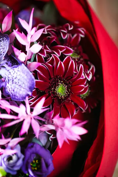 A vibrant bouquet of colorful flowers arranged in a red bag, with copy space available.