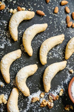 Yanında bir kase pudra şekerle çeşitli kurabiye ve fındık içeren bir masa..
