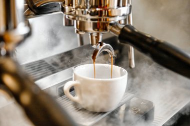 Bir fincan kahve demlemek için kahve makinesine dökülüyor..