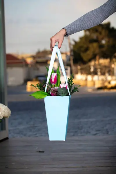 A person holds a flower pot filled with vibrant flowers, providing ample copy space.