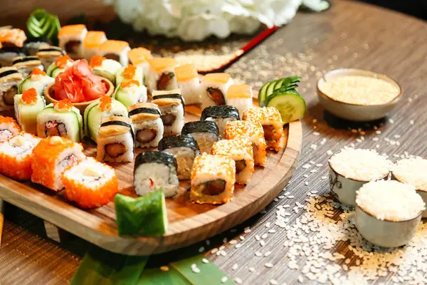 A wooden platter filled with various sushi rolls and nigiri pieces.