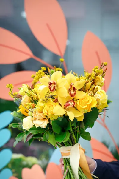A person holds a bouquet of yellow flowers with copy space.