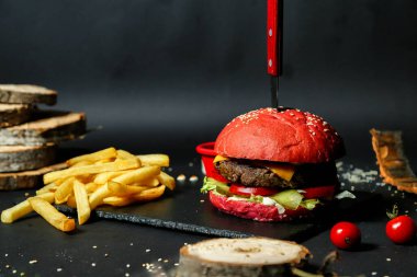 Bıçaklı bir hamburger, patates kızartmasının yanına konur..