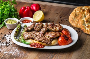 Beyaz tabak, besin değeri yüksek ve iştah açıcı bir yemek sunan rengarenk et ve sebzelerle dolu..