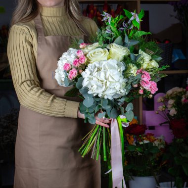 Bir kadın zarif bir şekilde elinde bir buket beyaz ve pembe çiçek tutar ve fazladan içeriğe yer açar..