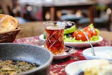 Bir tabak taze salatanın yanında lezzetli yiyeceklerle dolu çeşitli tabaklar sunan bir masa..
