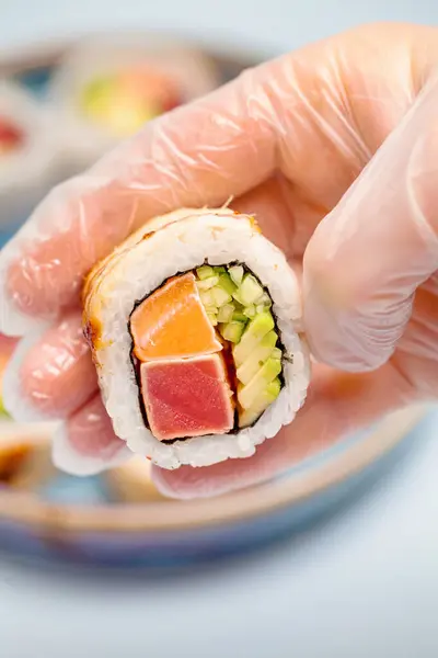 A person holding a piece of sushi in their hand, preparing to take a bite.