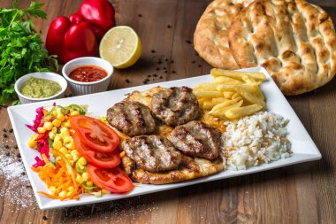 Beyaz bir tabağın üzerinde et, pirinç ve sebze aromalı bir karışım vardır..