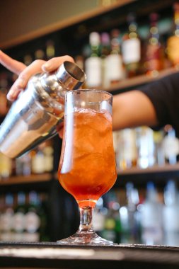 Bardağa içki dolduran bir insan bardağı içkiyle doldurma eylemini yakalar..