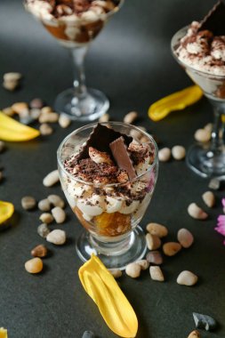 Masada küçük cam tabaklarda sunulan üç ayrı tatlının fotoğrafı..