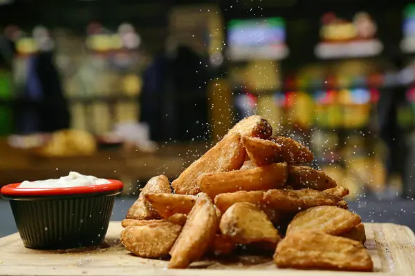A collection of fried food items arranged in a pile on top of a rustic wooden cutting board.