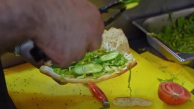 Bir insan tabakta sandviç kesmek için bıçak kullanıyor..