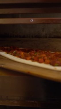 Sıcak fırında pişen pizzanın detaylı görüntüsü, peynirin erimesini ve kabuğunun kahverengileşmesini gösteriyor..