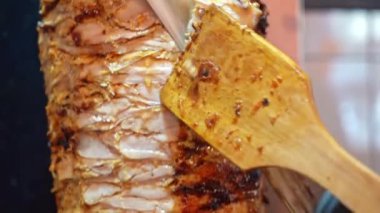 Büyük bir et parçasının yemek pişirme yüzeyinde bir spatulayla çevrilmesinin detaylı bir görüntüsü..