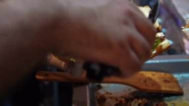 Bıçakla tahta kesme tahtasında yemek dilimleyen biri..