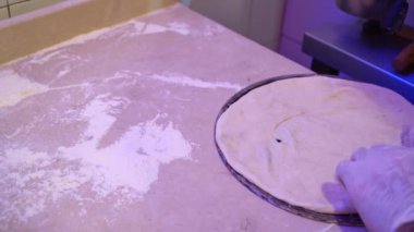 Mor eldiven giyen biri pizza hazırlıyor..