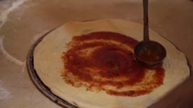 Tahta kesme tahtasındaki pizza bıçağıyla dilimlenen bir pizza..