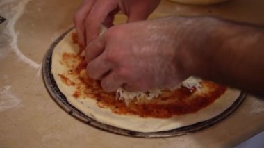Birisi pizza hamurunun üstüne peynir yayıp yoğuruyor..