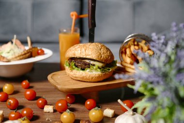 Lezzetli bir hamburger, her şey iştah açıcı bir şekilde sağlam bir ahşap kesme tahtasının üzerinde duruyor..