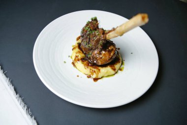 Beyaz bir tabak tuzlu sosla kaplı bir parça et içerir..