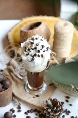 Taze demlenmiş kahveyle dolu bir fincan ve üzerine bol miktarda krema ve çikolata parçacıkları serpilmiş..