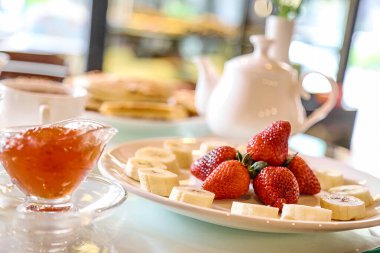 Bir tabak dolusu peynir ve taze çilek masaya konur..