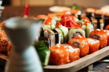 Çeşitli suşi dürümleri, nigiri ve sashimi ile dolu bir tepsi ahşap bir masaya düzgünce yerleştirilir..