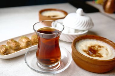 Bir fincan çay bir tabak yemeğin yanında görülür..