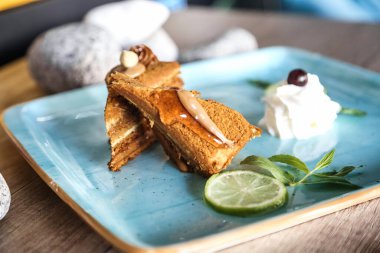 Mavi bir tabak kremalı kremayla kaplı lezzetli bir dilim pastayla süslenir..