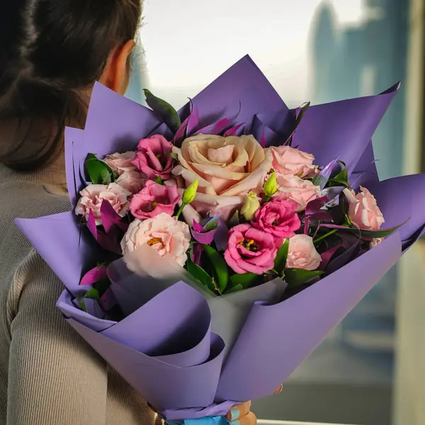 Boş bir arkaplanda güzel bir buket çiçek tutan bir kadın..