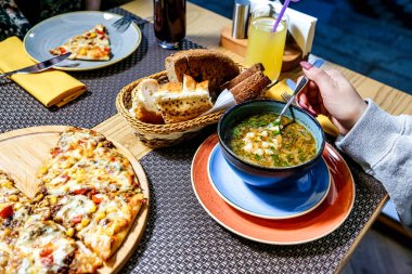 Çeşitli yemek tabakları ve bir kase sıcak çorba sergilenen bir masa..