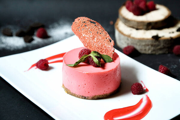 A visually appealing dessert featuring ripe raspberries arranged on a pristine white plate.
