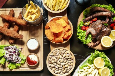 Bir masada lezzetli yemek ve patates kızartması dolu tabaklar sergilenir..