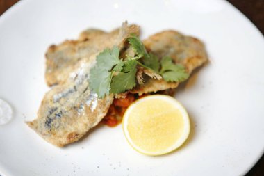 Lezzetli yiyeceklerle dolu beyaz bir tabak sağlam bir ahşap masanın üzerinde duruyor..