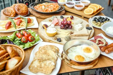 Meyveler, sebzeler, etler ve tatlılar da dahil olmak üzere çeşitli yemek çeşitleriyle dolu bir masa..