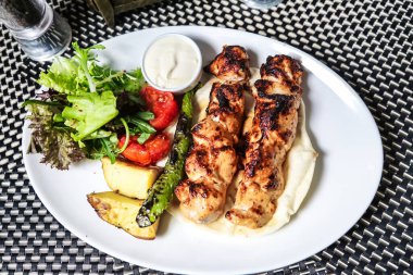 Havuç, brokoli ve dolmalık biber de dahil olmak üzere lezzetli bir tavuk ve çeşitli sebzelerle dolu beyaz bir tabak..