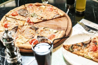 Erimiş peynirli yeni pişmiş bir pizza, lezzetli malzemeler, ve kırsal ahşap kesme tahtasının üzerinde gevrek bir kabuk var..