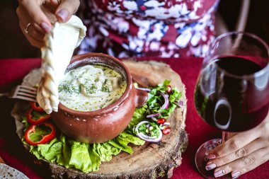 Bir insan lezzetli bir maddeyle dolu bir kaseye bir parça ekmek batırırken görülüyor..