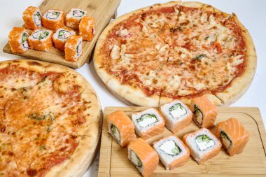 Bir masa pizza ve suşi ruloları ile kaplıdır..