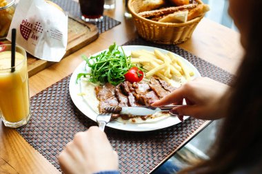 Bir insan, hareketli bir restoranda tabaktan lezzetli bir yemeğin tadını çıkarıyor..