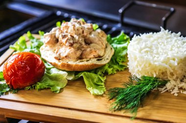 Sandviç ve pirinçle kaplı ahşap bir kesme tahtası protein ve karbonhidrat karışımı sergiliyor..