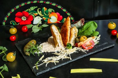 Lezzetli bir ekmek ve çeşitli taze sebzeler içeren siyah bir tabak..