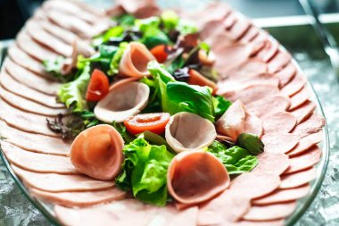 Bir tabağın ağız sulandırıcı yakın çekimi iştah açıcı yiyeceklerle dolu, titizlikle bir masaya yerleştirilmiş..