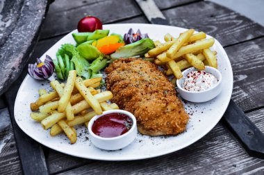 Beyaz tabak lezzetli baharatlı tavuk ve altın rengi patates kızartmasıyla doludur..