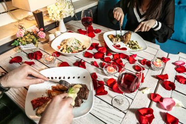 Önlerinde bir tabak lezzetli yemek varken bir masada oturup yemeğin tadını çıkaran iki insan..