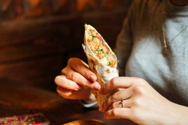 Bir insan elinde lezzetli bir dilim pizza tutar, ısırmaya hazırdır..